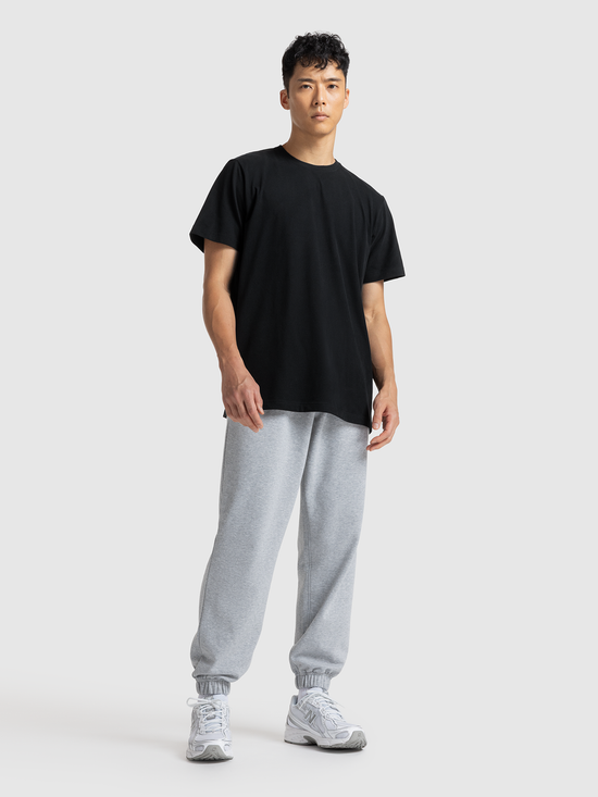 Person wearing a black t-shirt and gray sweatpants on a white background