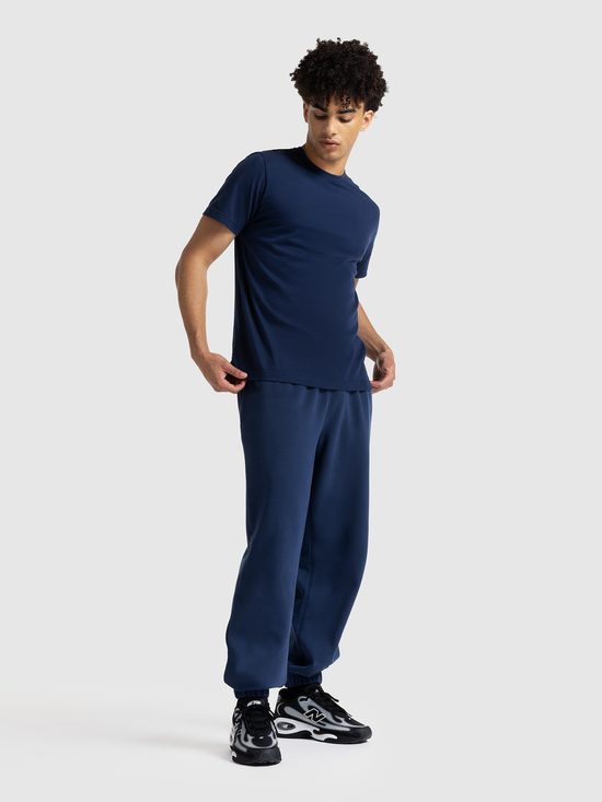 Person wearing a navy blue outfit with black sneakers on a white background