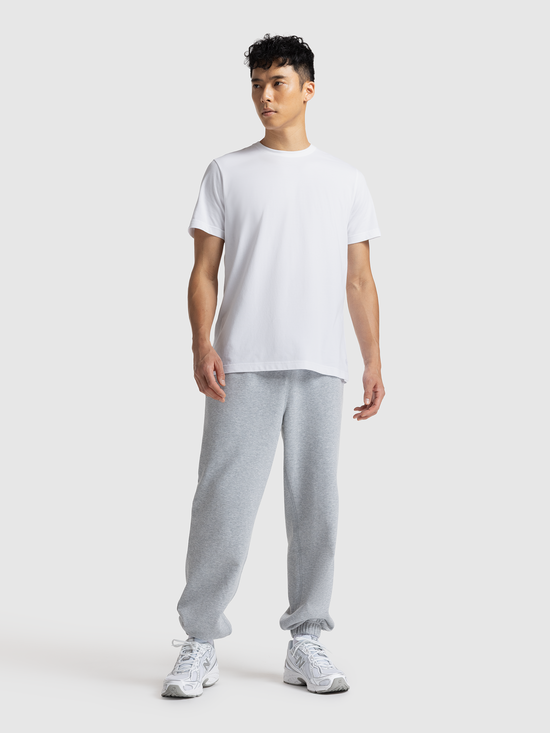 Person wearing a white t-shirt and gray sweatpants on a white background